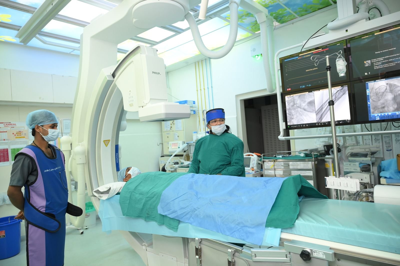 Cath lab staff in lead aprons beside the procedure table